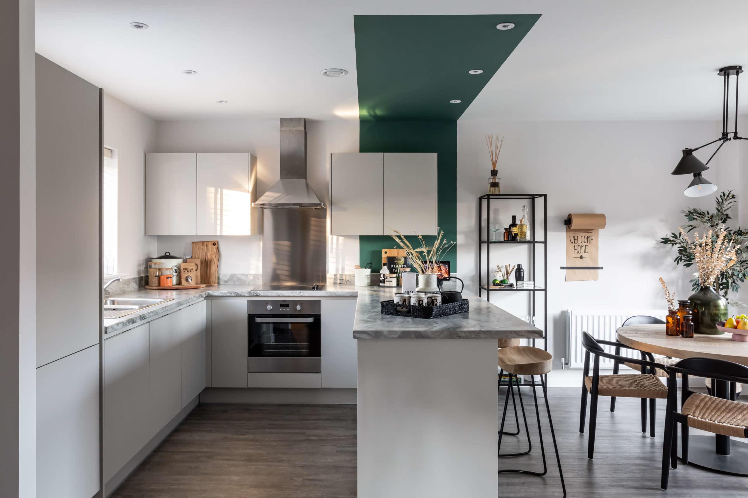 Kitchen with breakfast bar parallel with green strip of ceiling paint for zoning