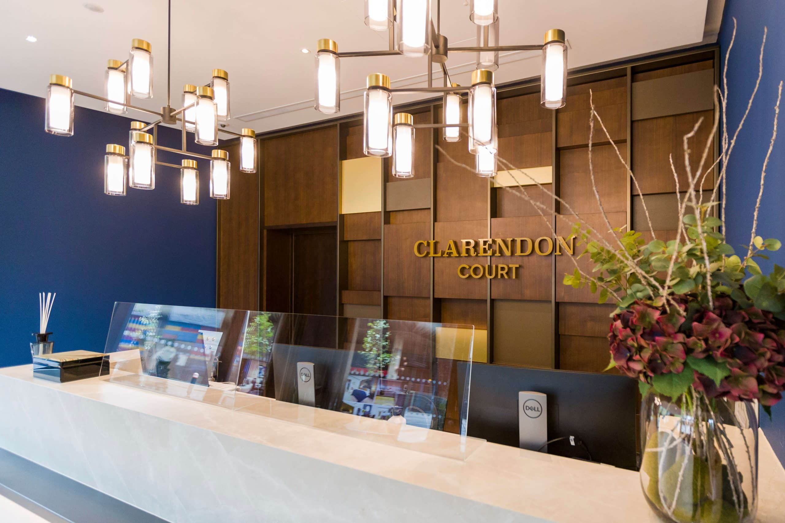 close-up of reception showing the desk, brass pendant lighting, and veneer backwall with brass detailing
