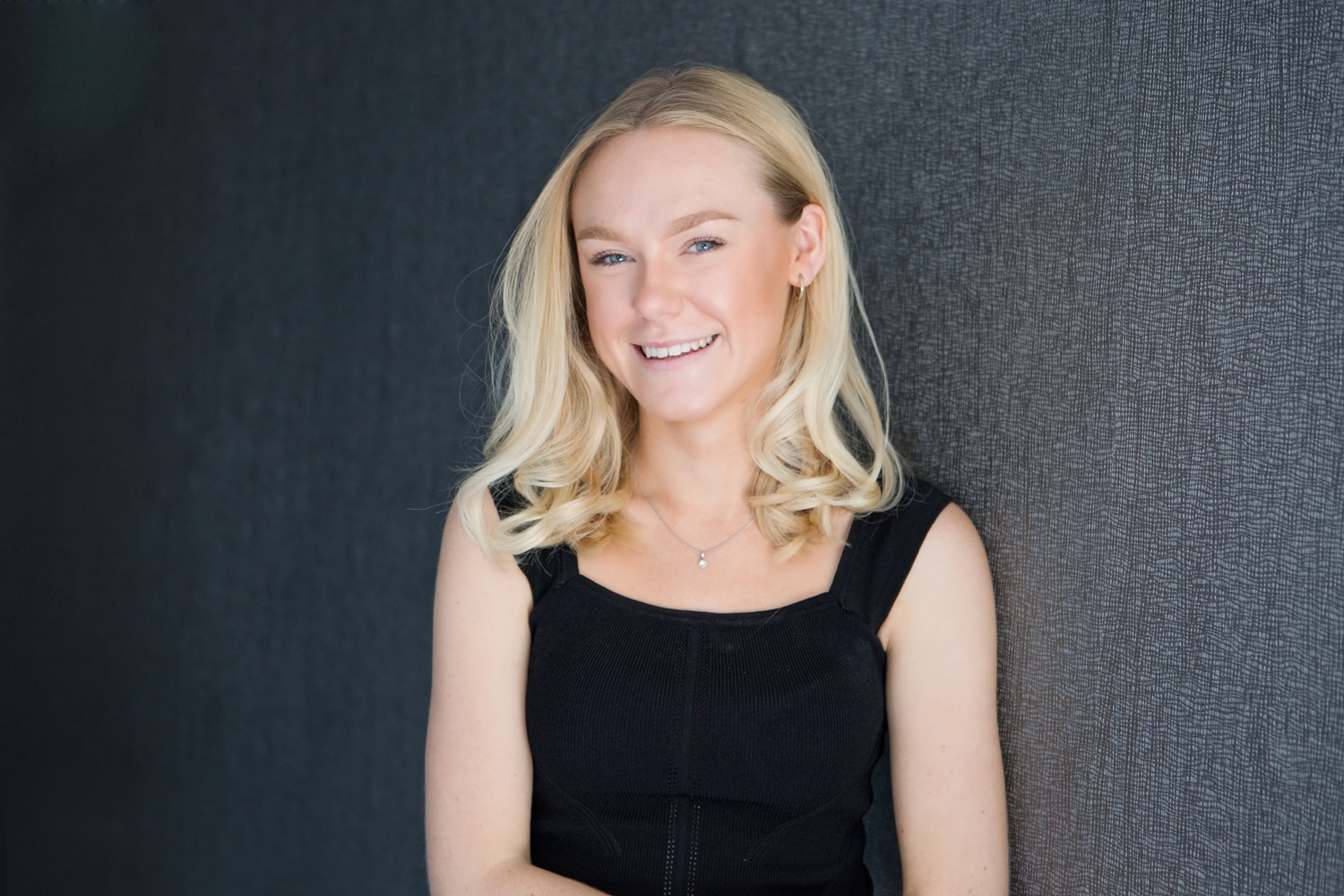 Charlotte Cook stood in front of dark grey wallpaper in Poole studio