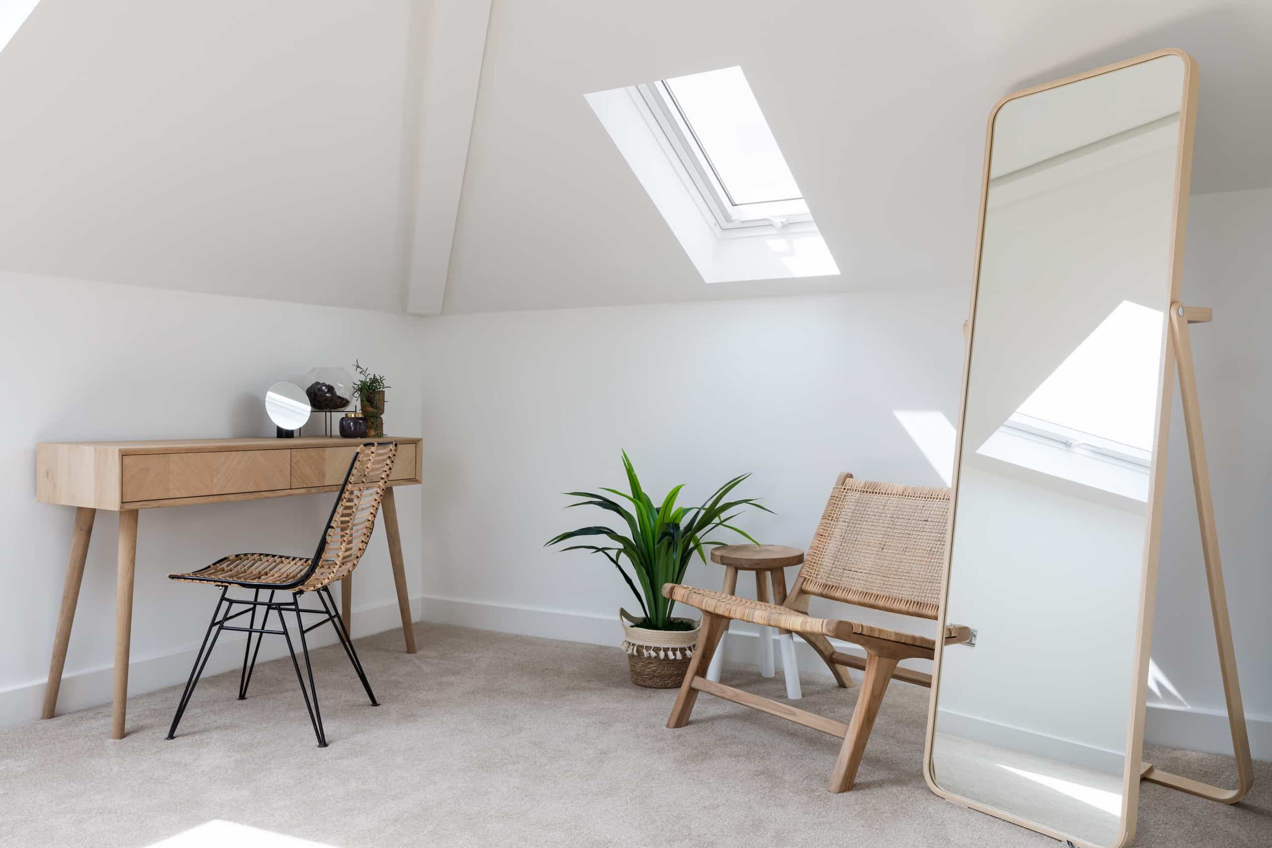 Corner of neutral wooden furniture with dark detailing to enhance corner of large master bedroom. Features a houseplant and curved full length mirror.